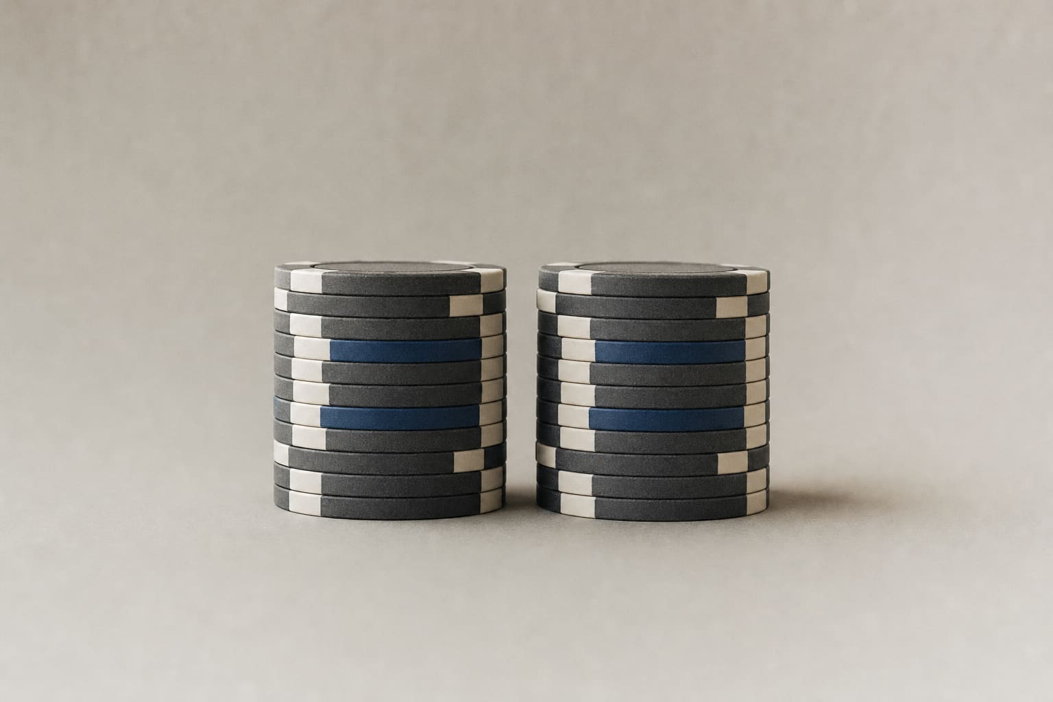 Two equal stacks of casino chips balanced side by side on a matte surface